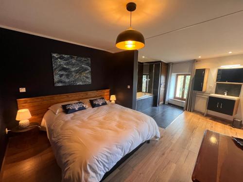 a bedroom with a large bed with a black wall at Suite parentale avec un petit salon in Homps