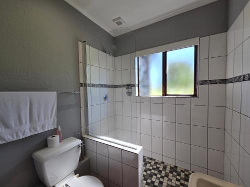 a bathroom with a toilet and a window at Azalea at Greenway Woods in White River