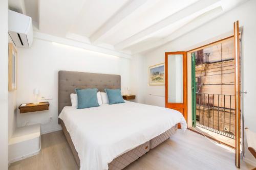 a white bedroom with a large bed and a window at Casa del Call in Palma de Mallorca