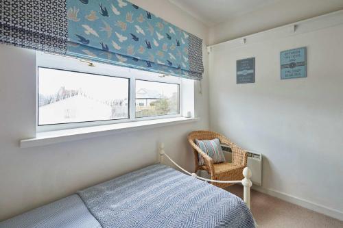 a bedroom with a bed and a window and a chair at The Bamburgh Bolthole in Bamburgh