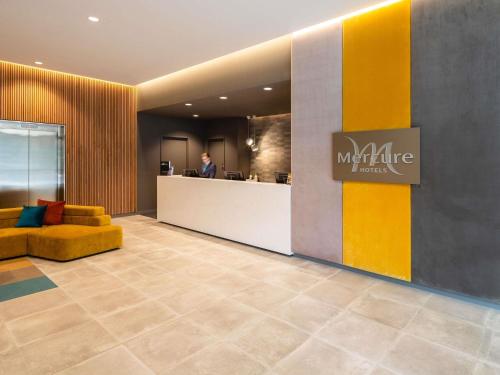 a man standing at a counter in a lobby at Mercure Canberra Belconnen in Canberra