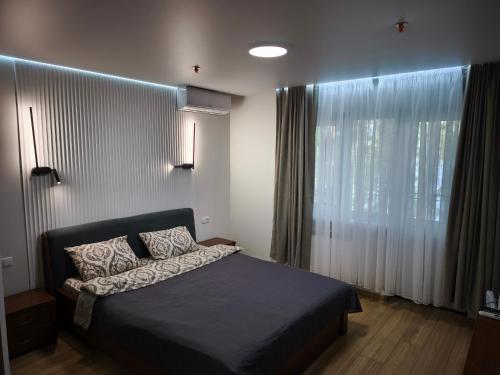 a bedroom with a bed and a large window at Бабай Садиба in Vasylʼkiv