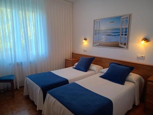 two beds in a hotel room with blue pillows at Pensión Bella Vista in Cóbreces