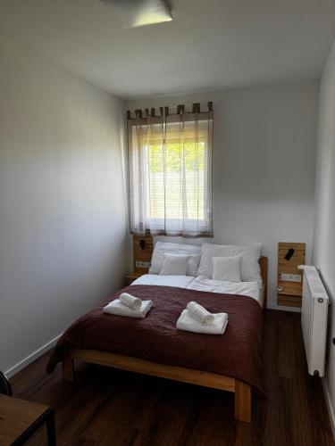 a bedroom with a large bed with two towels on it at Dominó Apartman in Gelse