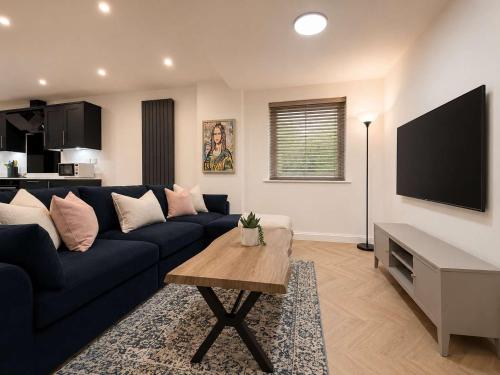 a living room with a blue couch and a flat screen tv at The Blackhorse Windsor in Dorney