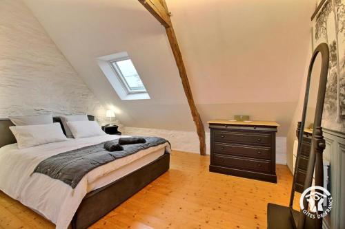 a bedroom with a bed with a dresser and a window at Le petit cottage in Ruffiac