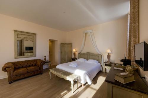 a bedroom with a bed and a couch and a television at Le Cara in Beaune