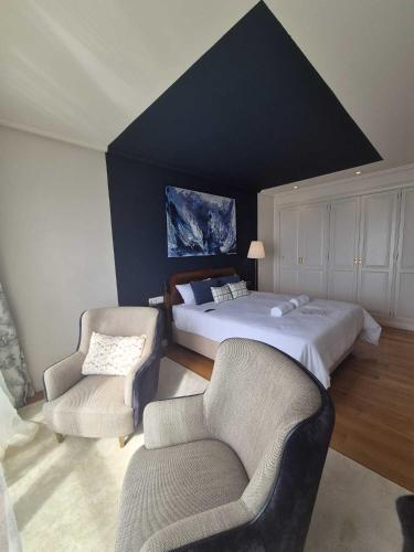 a bedroom with two beds and two chairs at Ocean View Room Oia in Oya