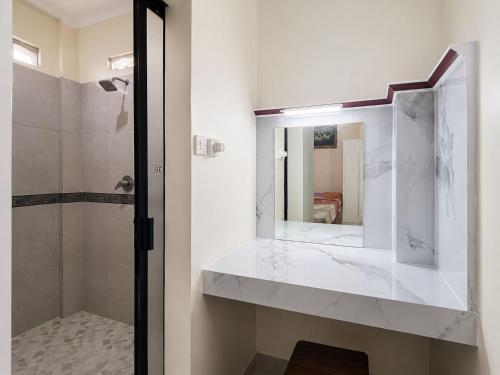 a white bathroom with a sink and a mirror at Satya Graha Hotel Yogyakarta in Yogyakarta