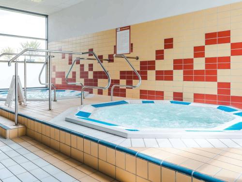 a hot tub in a room with a tile wall at ibis styles Bolesławiec in Bolesławiec