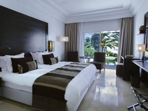 a hotel room with a large bed and a desk at Mövenpick Hotel Gammarth Tunis in Gammarth