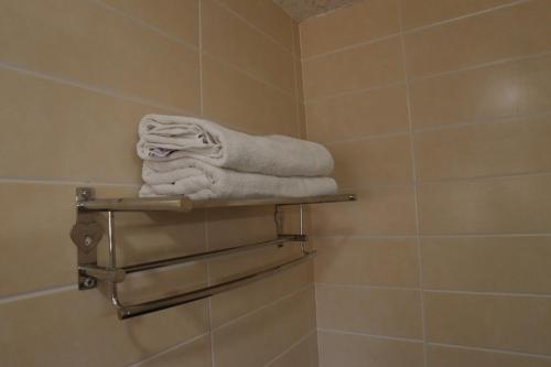 a pile of towels sitting on a shelf in a bathroom at PLA RESIDENCY Trichy near Rockfort Temple in Tiruchirappalli