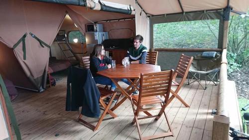 a man and woman sitting at a table in a tent at Camping 3 étoiles - ccbfige in Pouancé