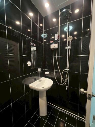 a black tiled bathroom with a sink and a shower at The Chill Town Home in Maha Sarakham
