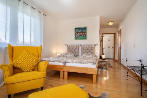 a bedroom with a bed and a yellow chair at Haus Grete in Langenargen