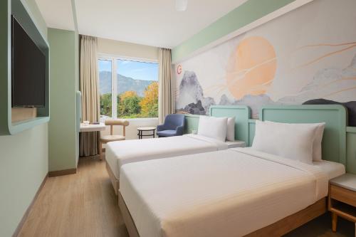 a hotel room with two beds and a tv at Ginger Ekta Nagar, Statue of Unity in Navgam