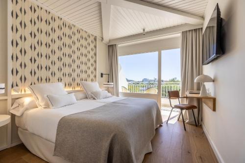 a bedroom with a large white bed and a window at Hoposa Panorama in Port de Pollensa