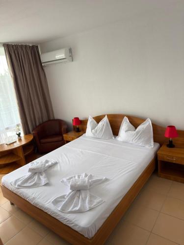 a bedroom with a large bed with white sheets at Hotel Mures in Saturn