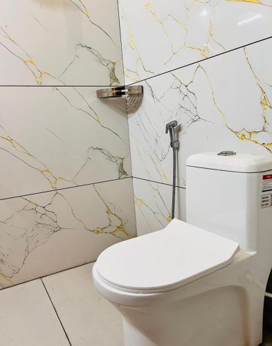 a white toilet in a bathroom with marble tiles at SJ Homes in Karukachal