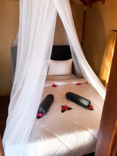 a bed with a canopy with two pillows on it at El-Mindri Bungalow dan Resto in Gili Gede
