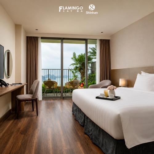 a hotel room with a large bed and a balcony at Flamingo Cát Bà in Cat Ba