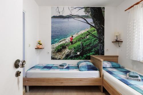 a bedroom with two beds and a picture of the ocean at Guest House Matana Pomena in Pomena