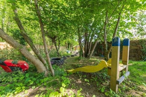a playground with a wooden fence and trees at Woods Meadow Glamping in West Malling