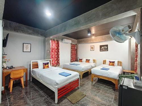 a room with two beds and a table and a desk at Ora House in San Kamphaeng