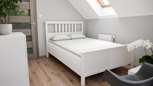 a white bedroom with a white bed and a window at Dom uKromki z kominkiem i widokiem na Śnieżkę in Sosnówka