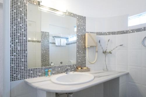 a white bathroom with a sink and a mirror at Long Beach Hotel & Resort in Lóngos