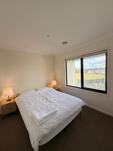a bedroom with a white bed and a large window at Shared House in Melbourne in Bundoora