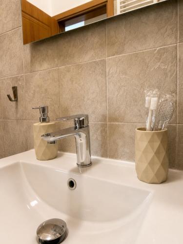 a bathroom sink with a faucet and tooth brushes at Asana by Agora Flats in Thessaloniki