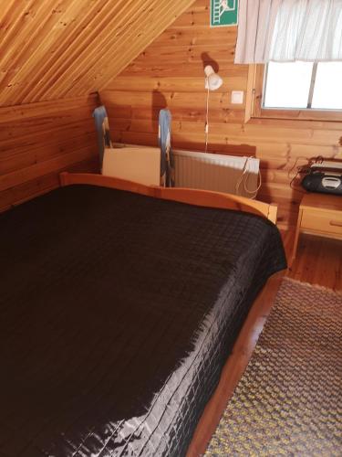a bedroom with a bed in a log cabin at Talvitahko 3 in Nilsiä