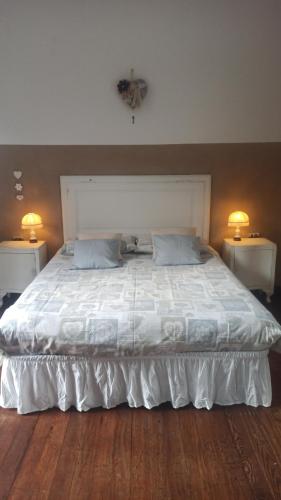 a large white bed with two tables and two lamps at Casa Clem centro Menaggio con possibilità di garage in Menaggio