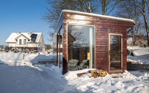 a small cabin in the snow with a window at Apartamenty U Harrego I Przy Stawie Spa z klimatyzacją, balia, sauna, ogrodem i parkingiem in Kudowa-Zdrój