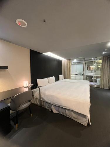 a bedroom with a large white bed and a desk at 鼎正國際商務旅館 in Taipei