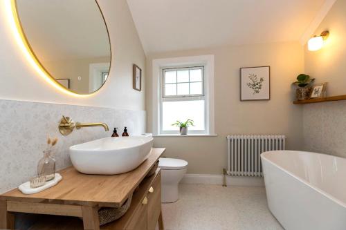 a bathroom with a large mirror and a tub and a sink at 2BR House By Cozy Quarters Property Management Holiday Lets Sedgefield With Open Field & Countryside Views in Sedgefield
