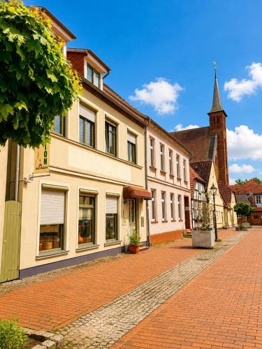 a cobblestone street with a building and a church at Pension am Bernsteinmuseum Ferienwohnung in Ribnitz-Damgarten