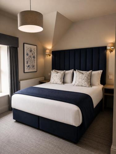 a bedroom with a large bed with a blue headboard at Powerscourt Arms Hotel in Enniskerry