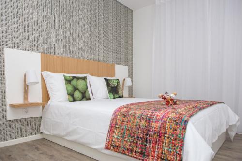 een slaapkamer met een wit bed en een kleurrijke deken bij The Marketplace by Storytellers in Funchal