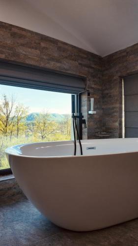 a bath tub in a bathroom with a large window at Casa YDA in Horezu