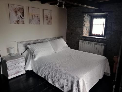 a bedroom with a white bed and a window at Flor de Pomar in Corao