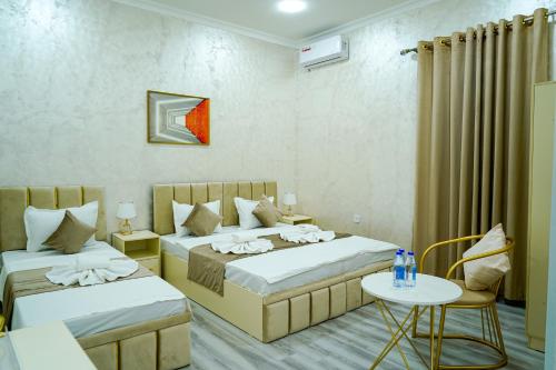 a hotel room with two beds and a table at Astoria Inn Hotel in Toshkent-Passajir Bekati
