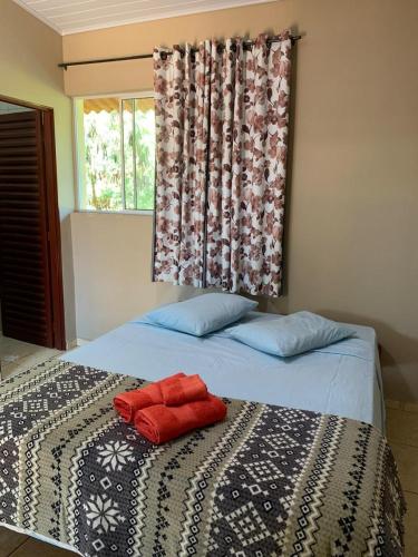 ein Bett mit zwei roten Kissen darauf in der Unterkunft Repouso do Tchê in Foz do Iguaçu