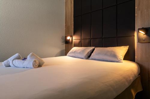 a large white bed with two towels on it at Hôtel Le Cyrano Bergerac in Bergerac
