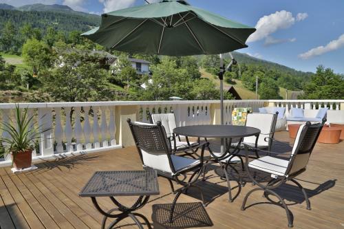 einen Tisch und Stühle mit einem Sonnenschirm auf einer Terrasse in der Unterkunft Garten- & Loggia-Appartement HERRENHAUS in Dellach im Drautal