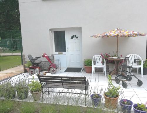 a patio with a bench and a table with an umbrella at Brise Fraîche de la Montagne-Piscine et Jacuzzi-Appartement Cottage au rez-de-chaussée in Le Poujol-sur-Orb