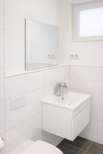 a white bathroom with a sink and a mirror at Ado Pension in Wedel