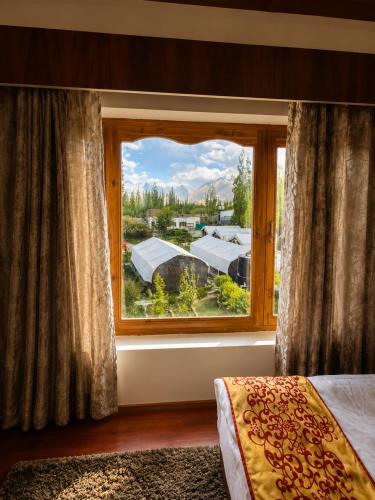 a bedroom with a large window with a view at Hotel Nubra Delight and Camps in Hundar