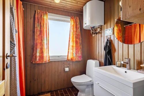 a bathroom with a toilet and a sink and a window at 5514-Hvide-Sande-Riskrogvej-18-C in Havrvig